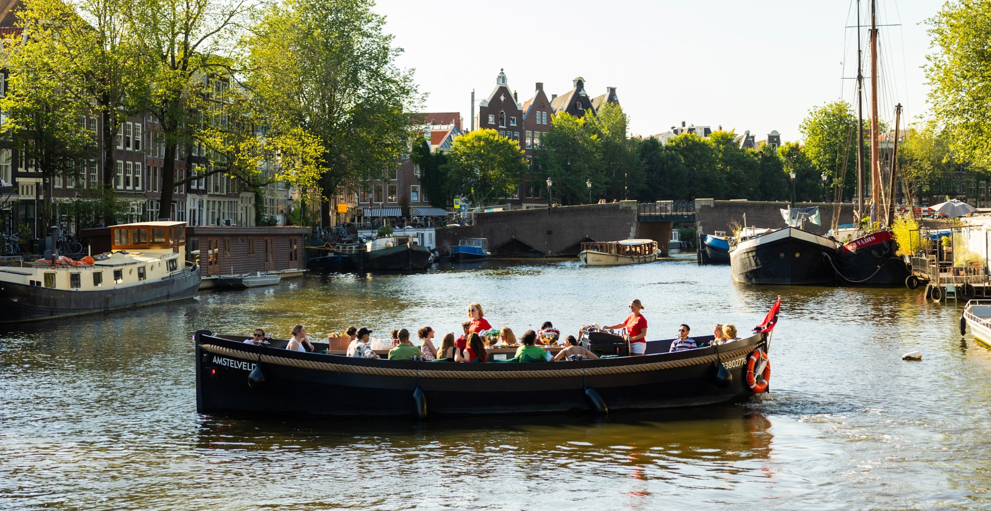 Open boot met een groep mensen die vaart over de Amsterdamse grachten. 