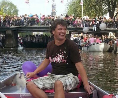 Man bestuurt een sloep tijdens Canal Parade in Amsterdam.